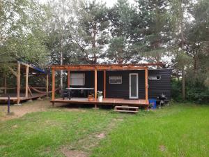 a black tiny house with a porch and a playground at Domek holenderski w Stadnine Koni Mazury in Łukta