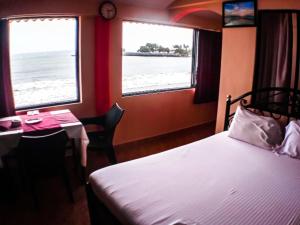 sypialnia z łóżkiem i stołem oraz 2 oknami w obiekcie Goan Delicacy Guest House w mieście Panaji