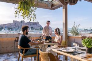 a man and woman sitting at a table with plates of food at Niche Hotel Athens in Athens