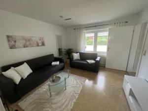 a living room with a black couch and a chair at Familienfreundliche Ferienwohnung mit Wintergarten in Badow