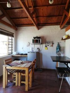 uma cozinha com uma mesa de madeira, uma mesa e cadeiras em Walvis Bay Backpackers & Self-catering em Walvis Bay