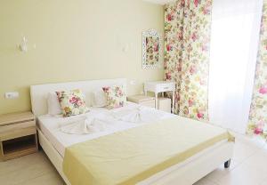 a bedroom with a large white bed with floral curtains at Family Hotel Sofi in Sozopol