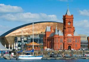 a building with a clock tower and a building with a boat in the water at Cardiff City centre Apartment lifestyle!! in Cardiff