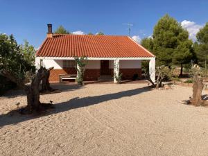 una casa con techo rojo y patio de tierra en Casa rural La Hontanilla, en Miguel Esteban