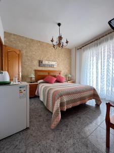 a bedroom with a bed with red pillows and a refrigerator at Pensión Mari Carmen in Salobreña