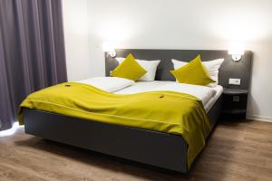 a bedroom with a large bed with yellow sheets and pillows at Das ELB Boardinghouse Hotel Restaurant in Magdeburg