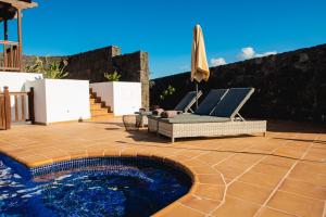 um pátio com uma piscina, uma cadeira e um guarda-sol em Villa DaVinci - Playa Blanca em Playa Blanca