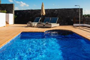 a swimming pool with two chairs and an umbrella at Villa DaVinci - Playa Blanca in Playa Blanca