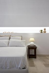 ポリニャーノ・ア・マーレにあるAnfora dei Segreti - Suite Apartmentの白いベッドルーム(白いベッド1台、テーブル付)