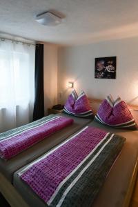 two beds in a room with purple sheets and pillows at Apartment Nerial in Bruck an der Großglocknerstraße