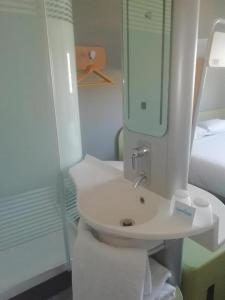 a white bathroom with a sink and a bed at SUN1 O.R.TAMBO in Johannesburg