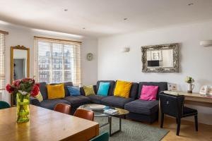 sala de estar con sofá azul y almohadas coloridas en PickThePlace Lancaster gate en Londres