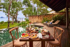 a table with food on a deck next to the water at The Tubkaak Krabi Boutique Resort in Tab Kaek Beach