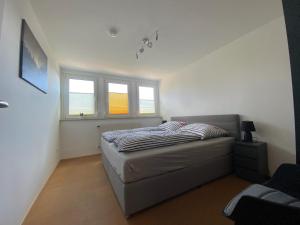 a small bedroom with a bed and two windows at Ferienwohnung am Holzberg in Volkach mit Weitblick in Volkach