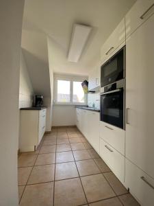 a kitchen with white cabinets and a tile floor at Ferienwohnung am Holzberg in Volkach mit Weitblick in Volkach