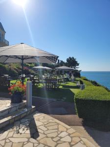 a patio with tables and umbrellas next to the ocean at Dormy House in Étretat