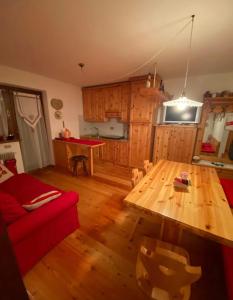 a living room with a wooden table and a red couch at Wood apartment in Canin ski resort in Sella Nevea