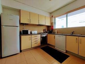 a kitchen with yellow cabinets and a white refrigerator at Jardiv's Apart in Ponta Delgada