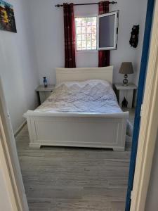 a bedroom with a white bed and a window at Au jardin d’Aghir: Villa arborée, avec piscine privée sans vis à vis! in Aghīr