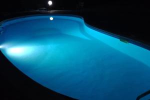 a blue swimming pool with a dark background at villa La Fornace in Campagnatico