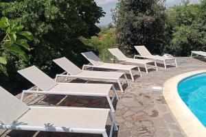 a row of white lounge chairs next to a swimming pool at villa La Fornace in Campagnatico