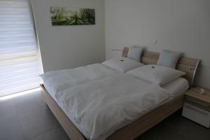 a bed with white sheets and pillows in a bedroom at FEWO Hof Elbbachtal in Westerburg