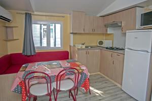 a small kitchen with a table and a red couch at Camping Village L'Apamée in Pamiers