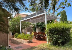 biała pergola na patio z krzesłami pod nim w obiekcie La Maison et son adorable jardin clos w Porquerolles