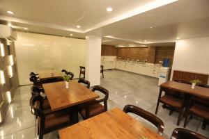 um restaurante com mesas e cadeiras de madeira e uma cozinha em Hotel Keshav Residency near Medanta Pure Veg em Gurgaon