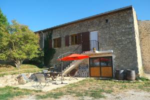 un bâtiment avec un escalier, un parasol et des chaises dans l'établissement Gîte Le Corral, à Cheminas