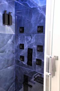 una ducha de azulejos azules con plazas negras en la pared en The Apartment, en Porto Santo Stefano