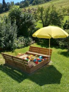 einen Sandkasten mit einem Regenschirm und Spielzeug darin in der Unterkunft Bio-Landhaus Kesslerhof in Gröbming