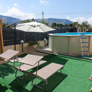 patio z krzesłami, parasolem i basenem w obiekcie Villa Torre Magaggiari w mieście Cinisi