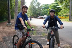 Zwei Männer reiten Fahrrad die Straße hinunter in der Unterkunft Beyond Angkor Homestay - Private Floor 2-Bedroom & Living Room in Siem Reap