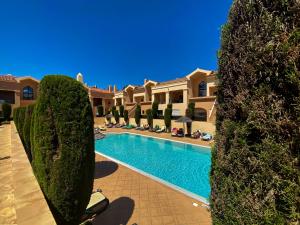 a villa with a swimming pool and some bushes at Baia da Luz - Nuzone Apartment in Luz