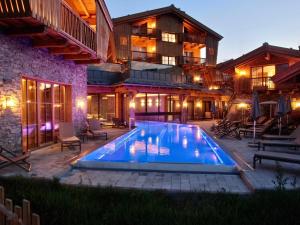 une maison avec une piscine en face d'un bâtiment dans l'établissement Chalet Village Zaglgut - Summercard Zell am See-Kaprun included, à Kaprun