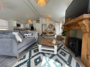 a living room with a gray couch and a fireplace at Hedgehog Lodge at Owlet Hideaway - with Hot Tub, near York in Seaton Ross