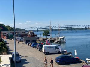 un gruppo di auto parcheggiate accanto a un fiume con un ponte di Dock House 95-97 a Middelfart