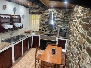een keuken met een tafel en een stenen muur bij Casa do Hiebra Alojamiento Rural Ribeira Sacra 
