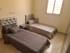 1 dormitorio con 2 camas y ventana en نزل الفيحاء en Riad