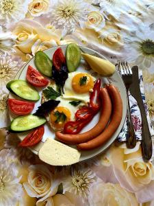 a plate with eggs sausage and vegetables on a table at Hotel Sali in Tbilisi City