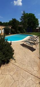 a swimming pool with two lawn chairs next to it at Kenguru Panzió és Csárda in Hódmezővásárhely