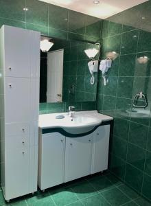 baño con lavabo blanco y azulejos verdes en Villa Alexa en Borovets