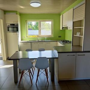 een keuken met groene muren en een tafel en stoelen bij Vakantiewoning Op Den Briel in Lokeren