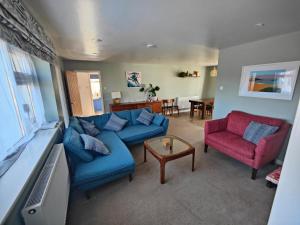 a living room with a blue couch and two red chairs at Seaside bungalow 5 mins walk to beach and town in Bude