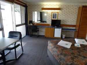 a room with a bed and a table and a tv at Gayndah A Motel in Gayndah