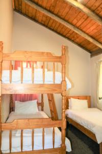 a bedroom with two bunk beds with white sheets at Malolotja Log Cabins in Mbabane