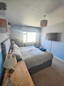 a bedroom with a bed with a table and a window at Seaside bungalow 5 mins walk to beach and town in Bude