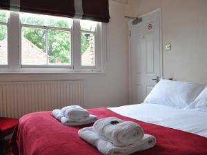 a bedroom with towels on a bed with a window at Rose and Crown B&B in Burwash