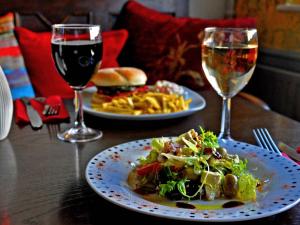 a table with two plates of food and two glasses of wine at Rose and Crown B&B in Burwash